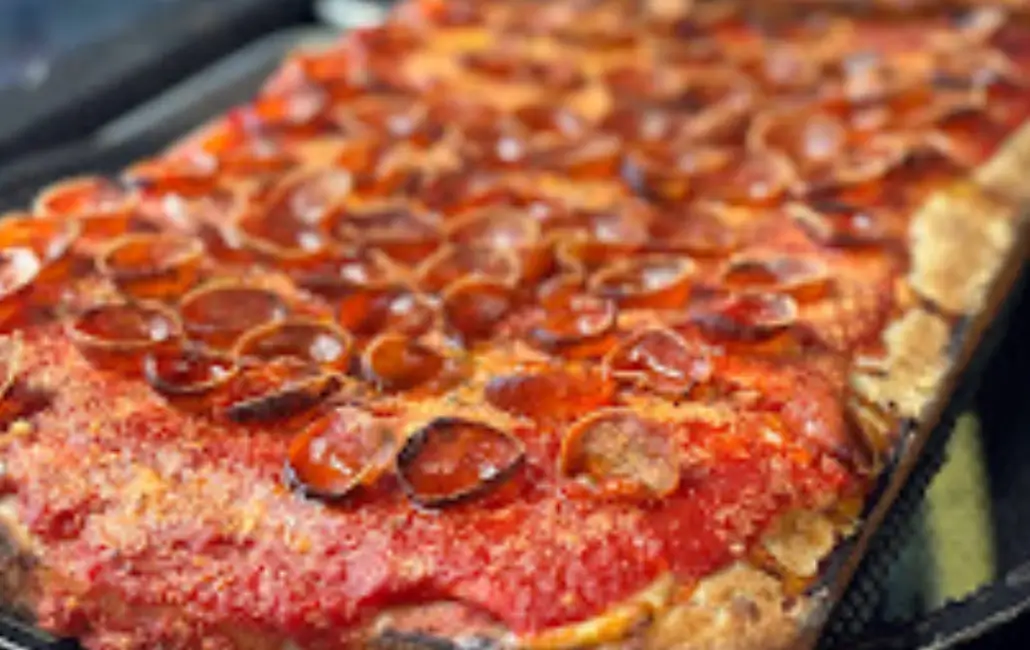 A close up of pepperoni pizza on top of a pan.